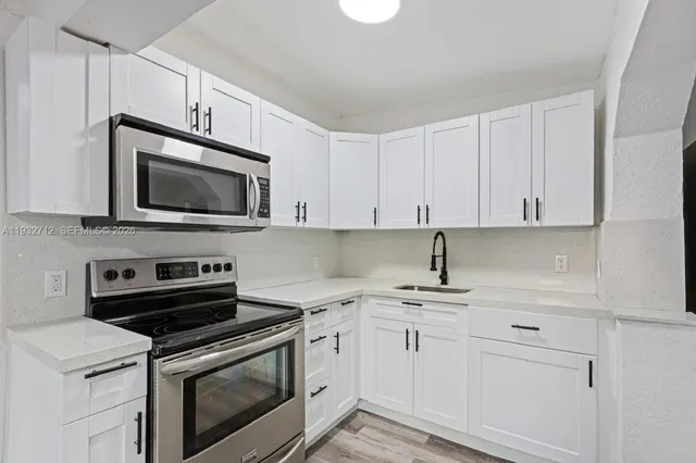 a kitchen with cabinets stainless steel appliances and sink