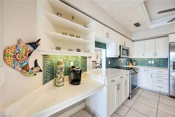 a kitchen with stainless steel appliances kitchen island granite countertop a refrigerator a stove and white cabinets