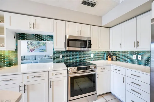a kitchen with white cabinets and stainless steel appliances