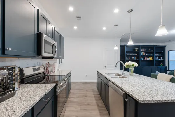 a kitchen with stainless steel appliances granite countertop a sink a stove and a wooden floors