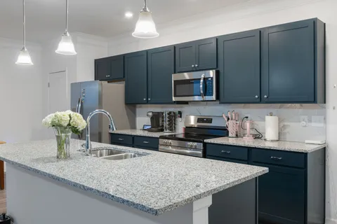 a kitchen with granite countertop a sink a counter top space cabinets and stainless steel appliances