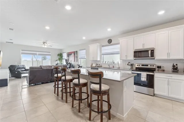 a kitchen with sink a refrigerator and chairs