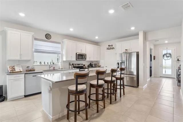 a large white dining hall with stainless steel appliances granite countertop a large center island and a sink