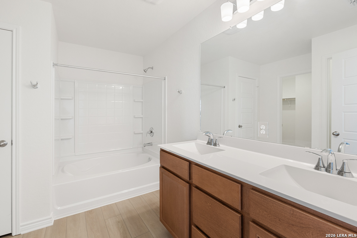 10045 Jagger Avenue Converse, TX 78109 - Photo 19 of 28 a bathroom with a sink a bathtub a mirror and a shower