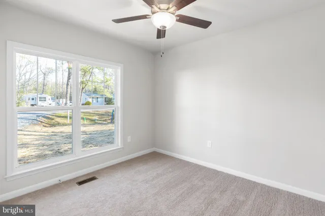 an empty room with windows and ceiling fan