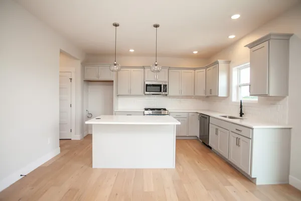 a kitchen with stainless steel appliances granite countertop a sink a stove a refrigerator and white cabinets