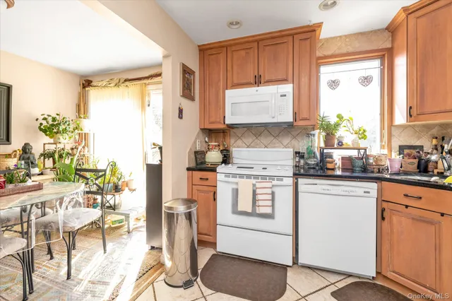 a kitchen with stainless steel appliances granite countertop a refrigerator a stove a sink and white cabinets with wooden floor