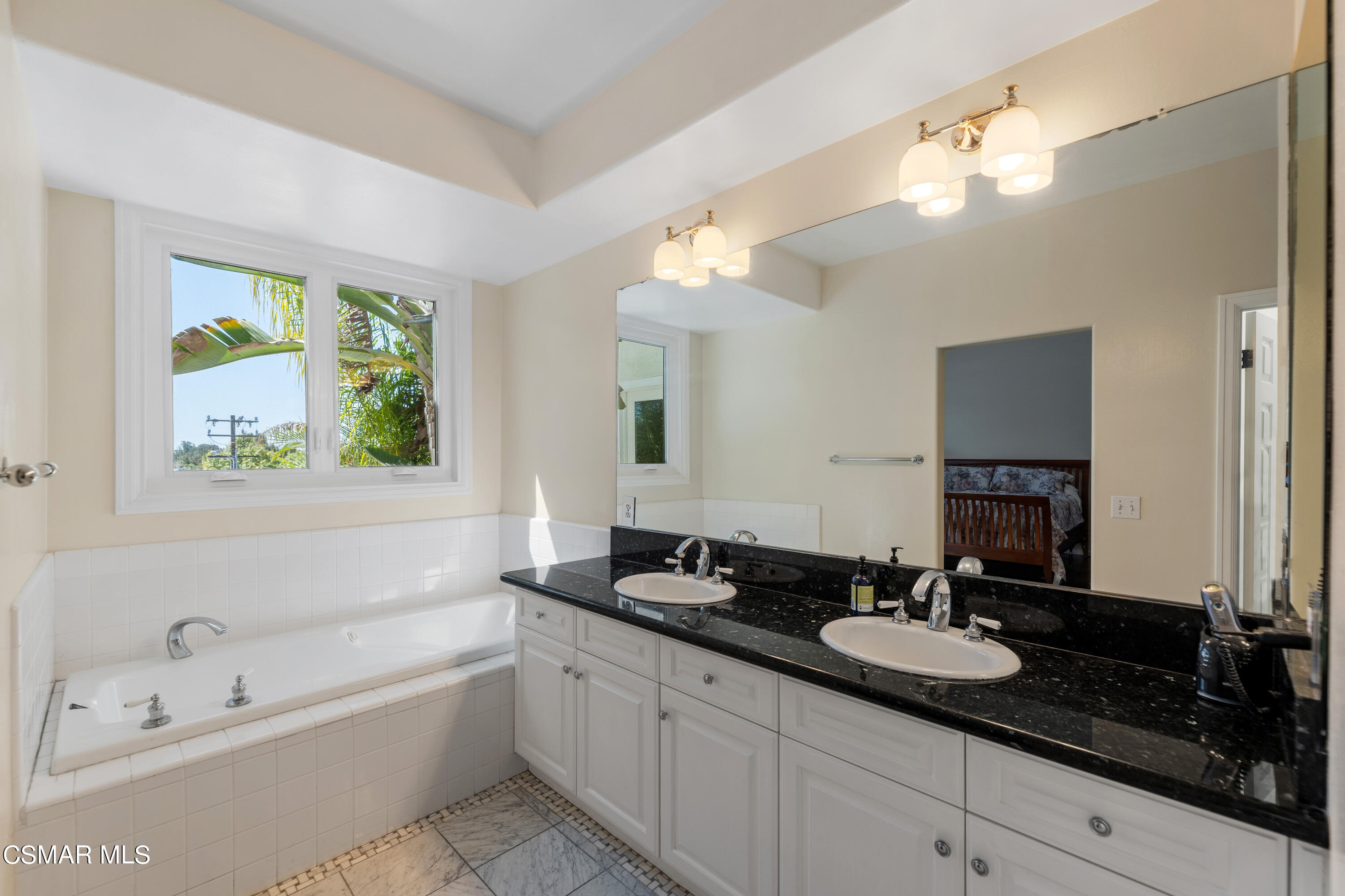 6435 Zumirez Drive, Unit 15 Malibu, CA 90265 - Photo 23 of 38 a bathroom with a granite countertop sink a large mirror a bathtub and window