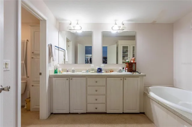 a bathroom with a double vanity sink mirror and bathtub
