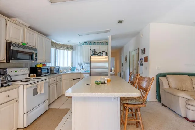 a kitchen with stainless steel appliances kitchen island granite countertop a sink a stove a table and chairs