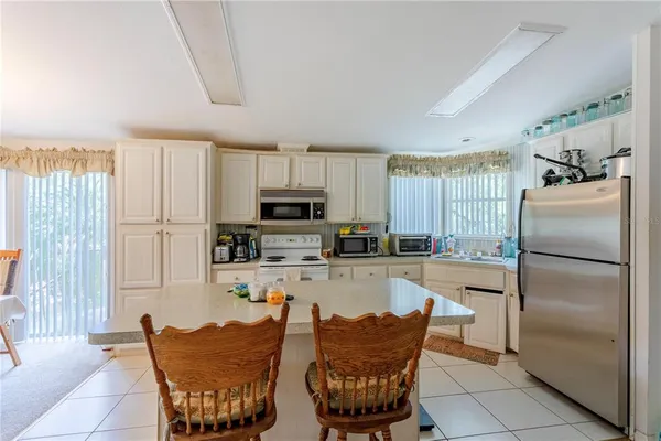 a kitchen with stainless steel appliances granite countertop a refrigerator a stove a sink a dining table and chairs with wooden floor