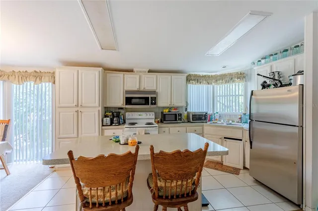 a kitchen with stainless steel appliances granite countertop a refrigerator a stove a sink a dining table and chairs with wooden floor