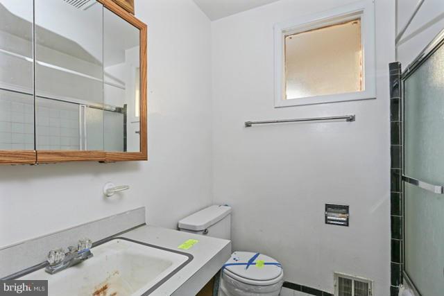 8704 Riggs Road Hyattsville, MD 20783 - Photo 13 of 25 a bathroom with a sink a toilet and a mirror