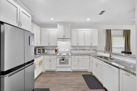 a kitchen with a sink stove cabinets and refrigerator