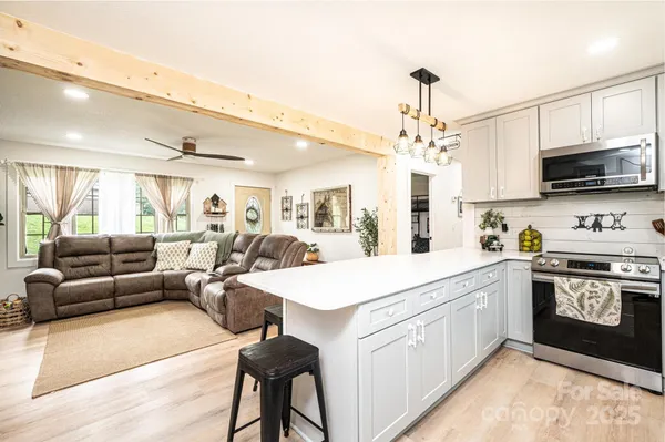 a large white kitchen with stainless steel appliances granite countertop a lot of cabinets a sink and a stove