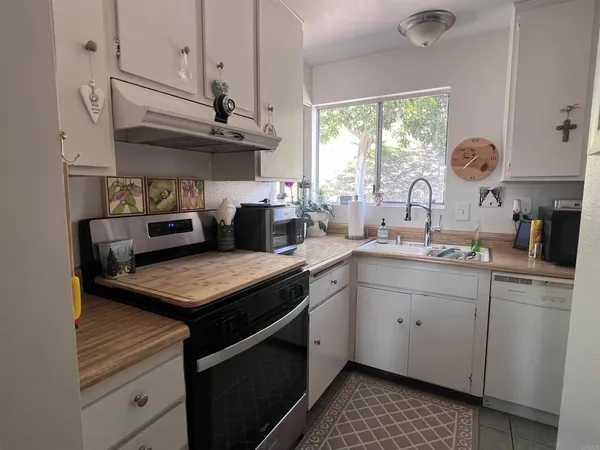a kitchen with stainless steel appliances granite countertop a sink a stove a refrigerator a window and cabinets