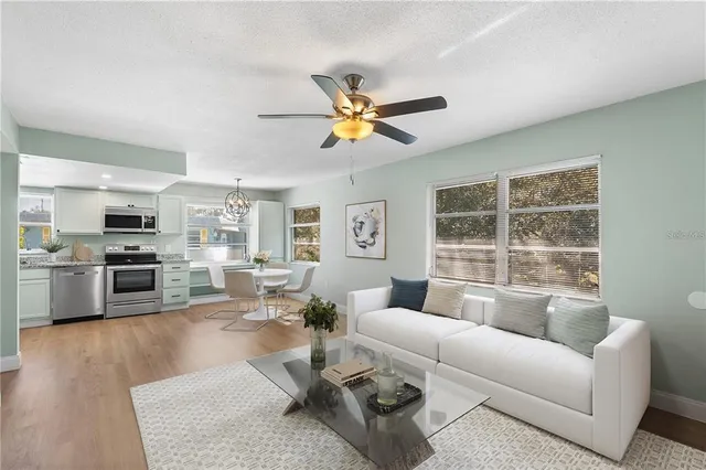 a living room with furniture kitchen view and a large window