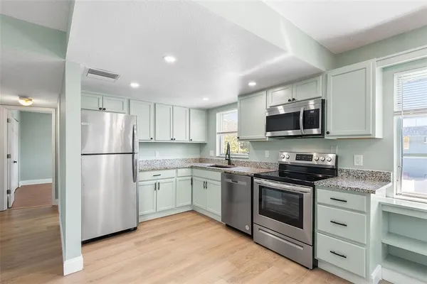 a kitchen with stainless steel appliances granite countertop a refrigerator stove a sink dishwasher a microwave oven with cabinets and wooden floor