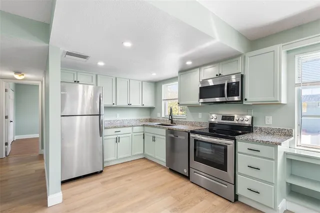 a kitchen with stainless steel appliances granite countertop a refrigerator stove a sink dishwasher a microwave oven with cabinets and wooden floor