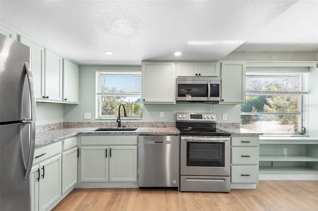 a kitchen with stainless steel appliances granite countertop a stove a sink and a microwave