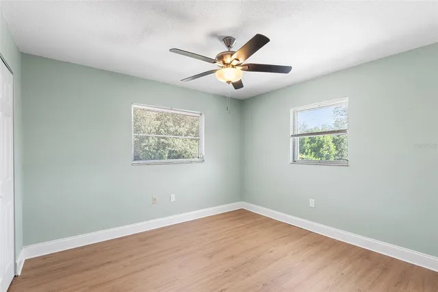 an empty room with wooden floor and ceiling fan