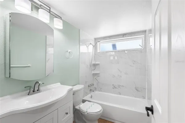 a bathroom with a bathtub shower sink vanity mirror and toilet