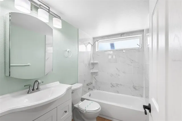 a bathroom with a bathtub shower sink vanity mirror and toilet