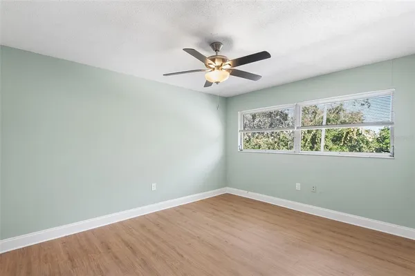 an empty room with a window and ceiling fan