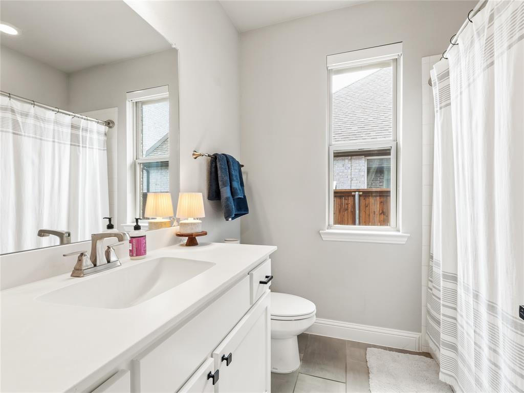 15340 Crape Myrtle Road Frisco, TX 75035 - Photo 28 of 40 White vanity with an integrated sink and brushed nickel faucet, a large wall mirror, and a window with blinds