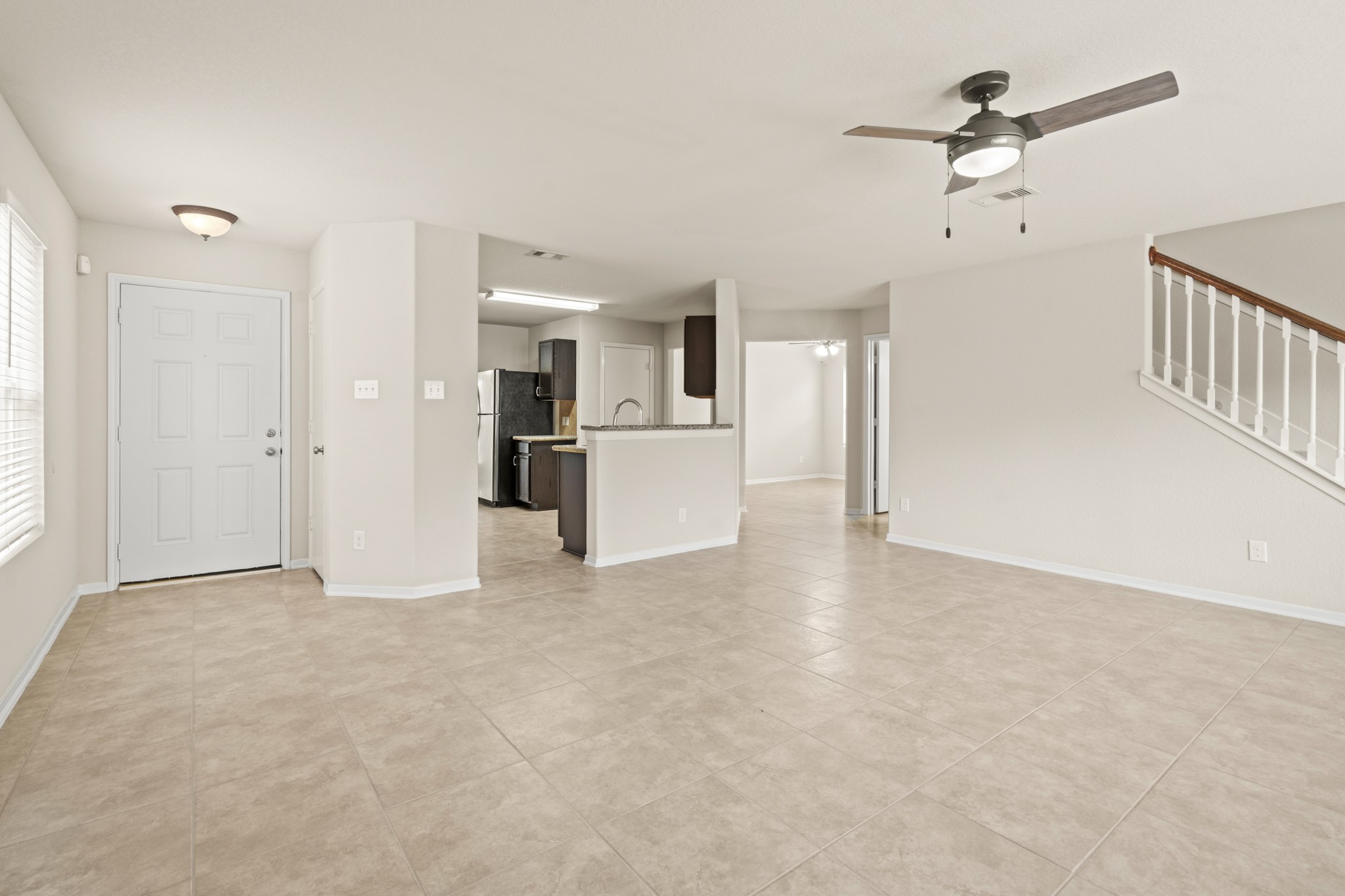 3118 Winchester Rnch Trail Katy, TX 77493 - Photo 3 of 22 This angle captures the home's wonderful open-concept flow, with the family room seamlessly connecting to the kitchen beyond. The modern ceiling fan, tile floors, and a glimpse of the granite kitchen peninsula with dark cabinetry make this a space designed for easy everyday living and family connection.