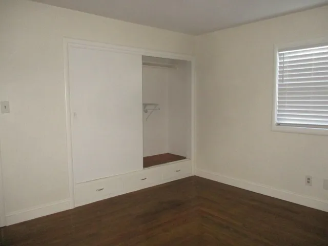 an empty room with wooden floor and white walls