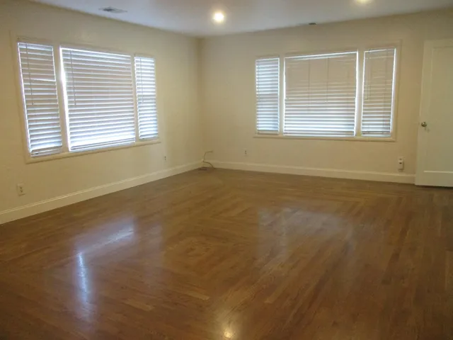 a view of an empty room with wooden floor and a window