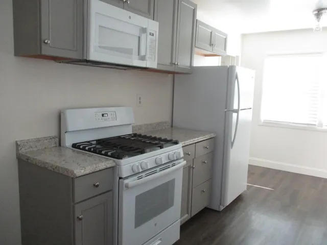 a kitchen with granite countertop cabinets appliances and wooden floor