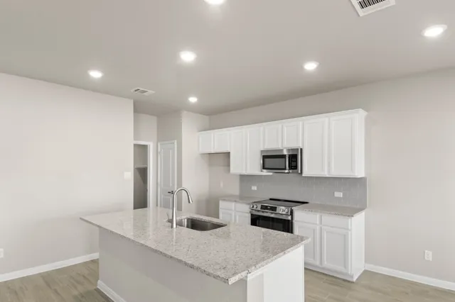 a view of an empty room with kitchen and window