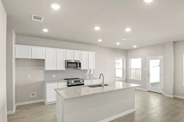 a kitchen with stainless steel appliances granite countertop a sink a stove and a refrigerator