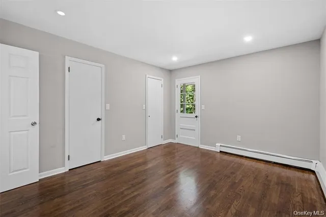a view of an empty room with wooden floor and closet