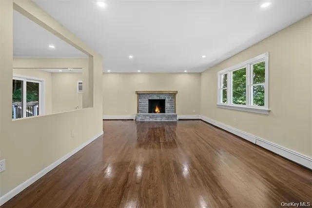 an empty room with wooden floor fireplace and windows