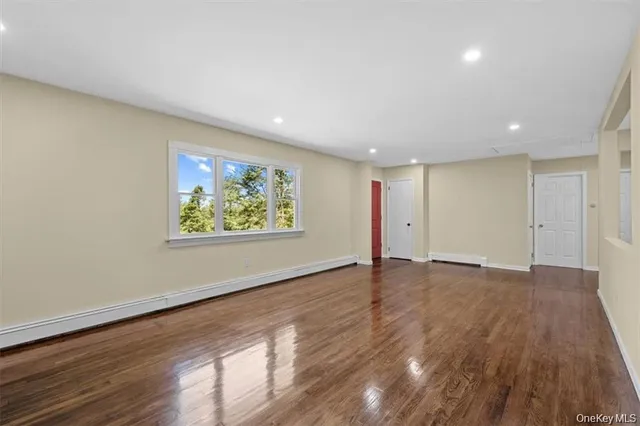 a view of an empty room with wooden floor and window