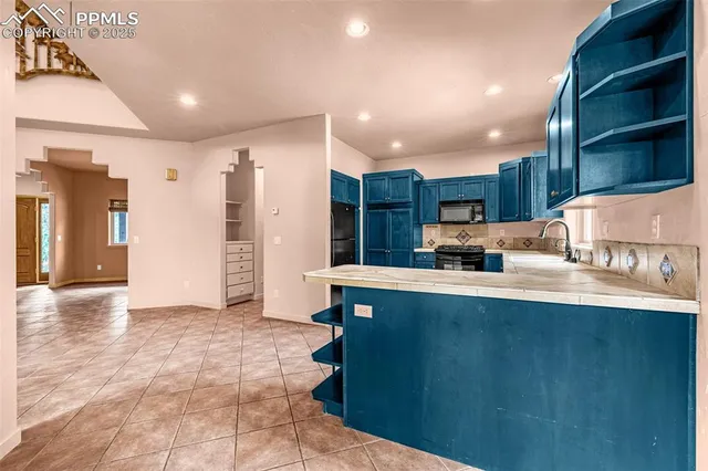 a large kitchen with stainless steel appliances a large counter top a stove and a refrigerator