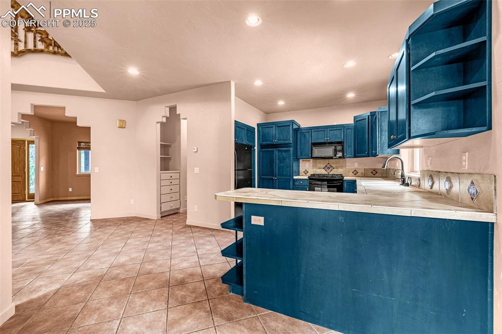 9890 Hardy Road Colorado Springs, CO 80908 - Photo 8 of 41 a large kitchen with stainless steel appliances a large counter top a stove and a refrigerator