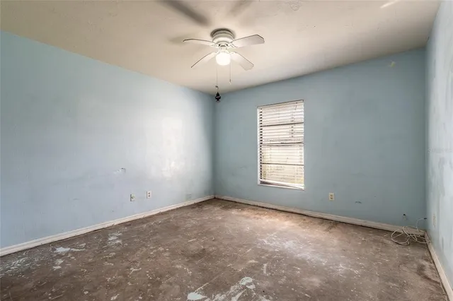 an empty room with windows and chandelier fan