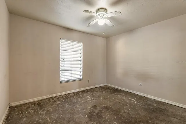 an empty room with a window and a fan