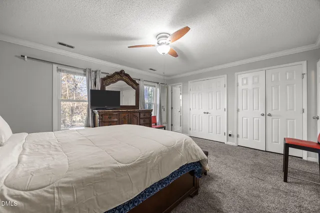 a spacious bedroom with a bed and a dresser with mirror