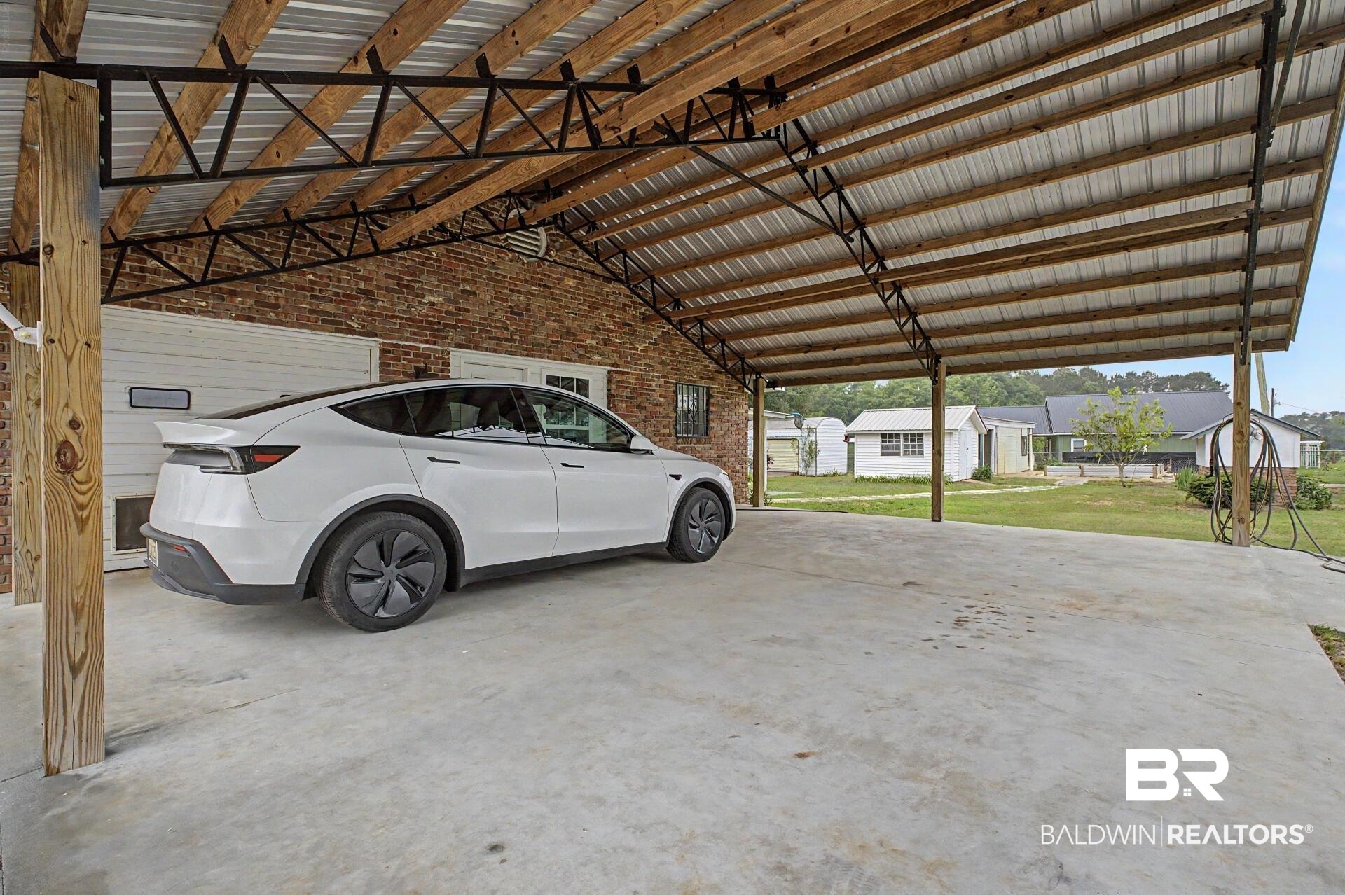 3791 Robinsonville Road Atmore, AL 36502 - Photo 4 of 47 Expansive concrete carport with a metal roof and exposed wood beams