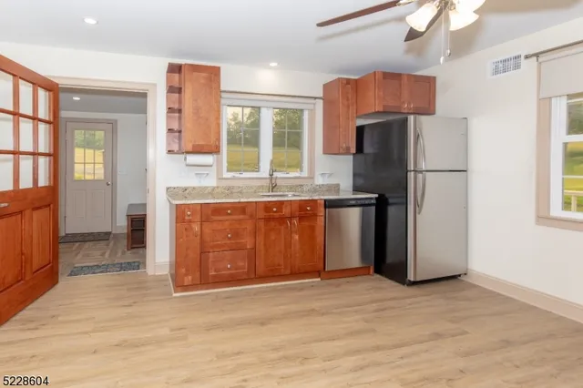 a kitchen with stainless steel appliances granite countertop a refrigerator a stove a sink and a large window