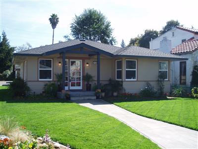 a view of a yard in front of a house with plants and large tree