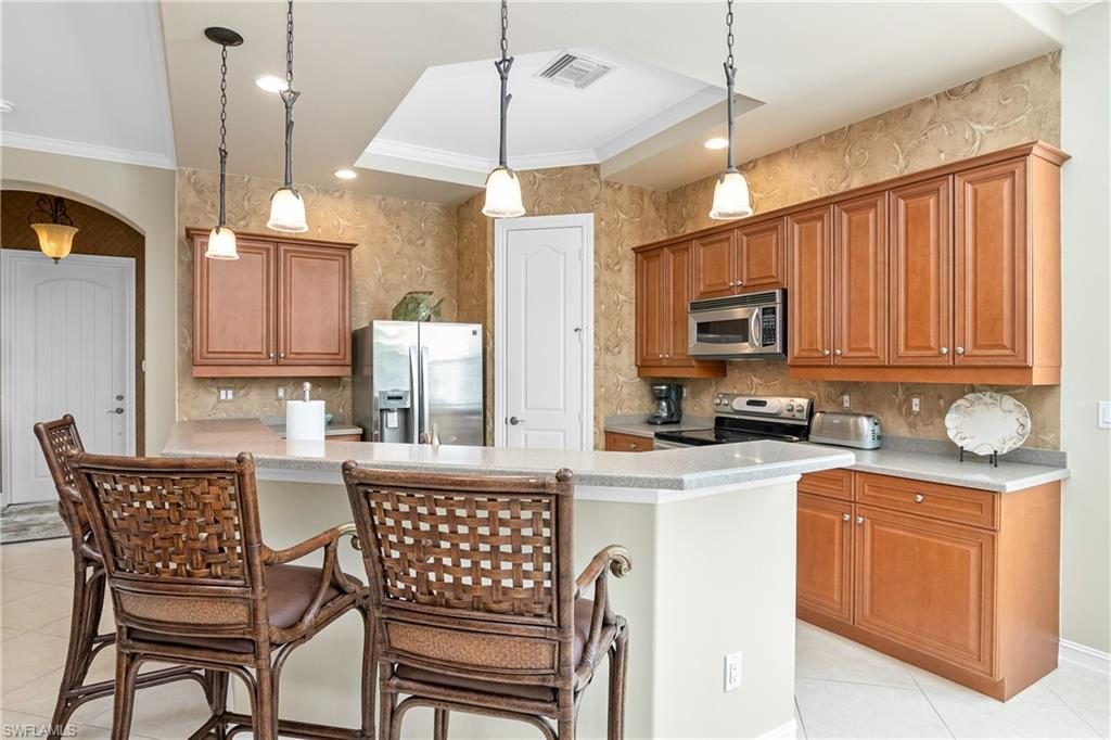 1349 Serrano Circle Naples, FL 34105 - Photo 18 of 37 a kitchen with stainless steel appliances kitchen island granite countertop a stove a sink dishwasher a dining table and chairs with wooden floor