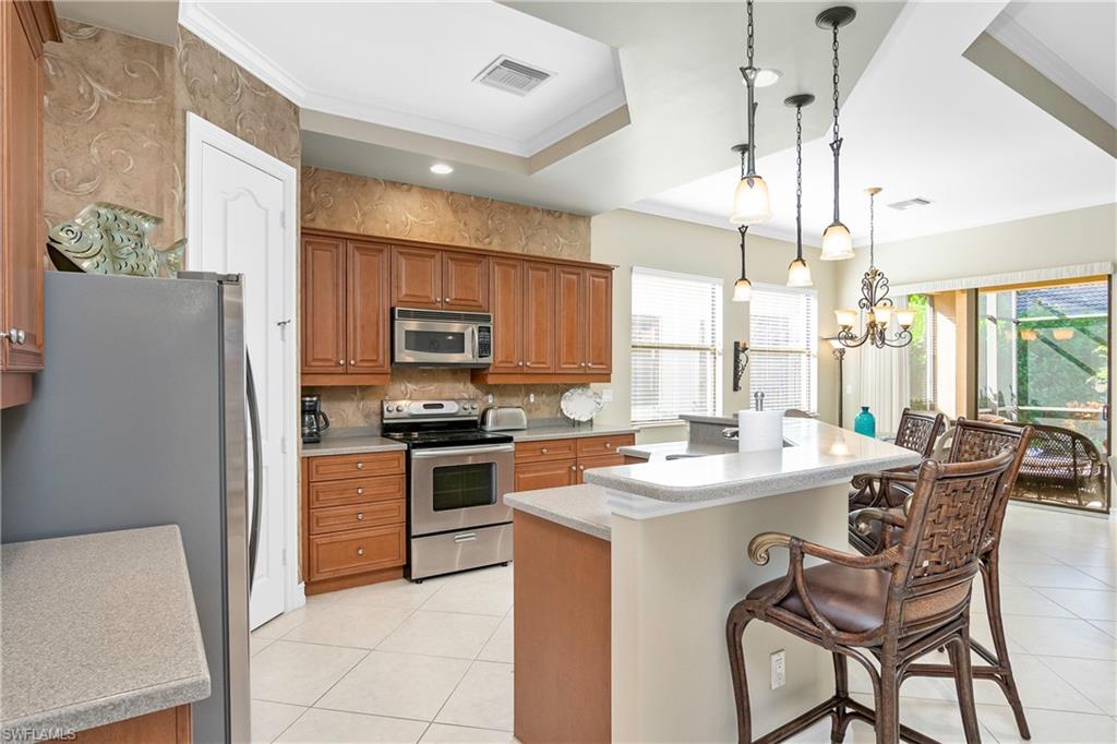 1349 Serrano Circle Naples, FL 34105 - Photo 19 of 37 a kitchen with stainless steel appliances granite countertop a stove a refrigerator a sink dishwasher a dining table and chairs with wooden floor