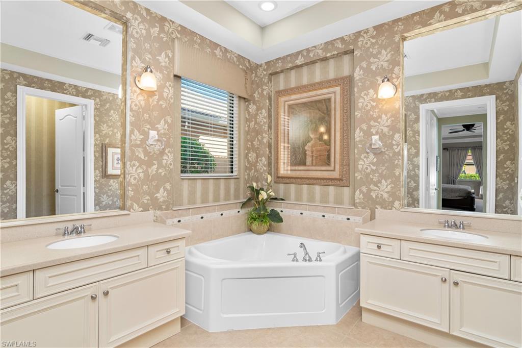 1349 Serrano Circle Naples, FL 34105 - Photo 4 of 37 a bathroom with a bathtub a double vanity sink a window and a mirror