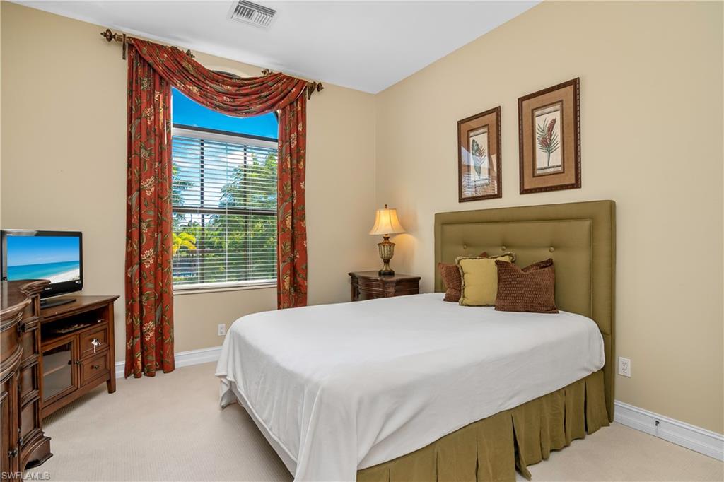 1349 Serrano Circle Naples, FL 34105 - Photo 9 of 37 a bedroom with a bed and a flat tv screen on dresser